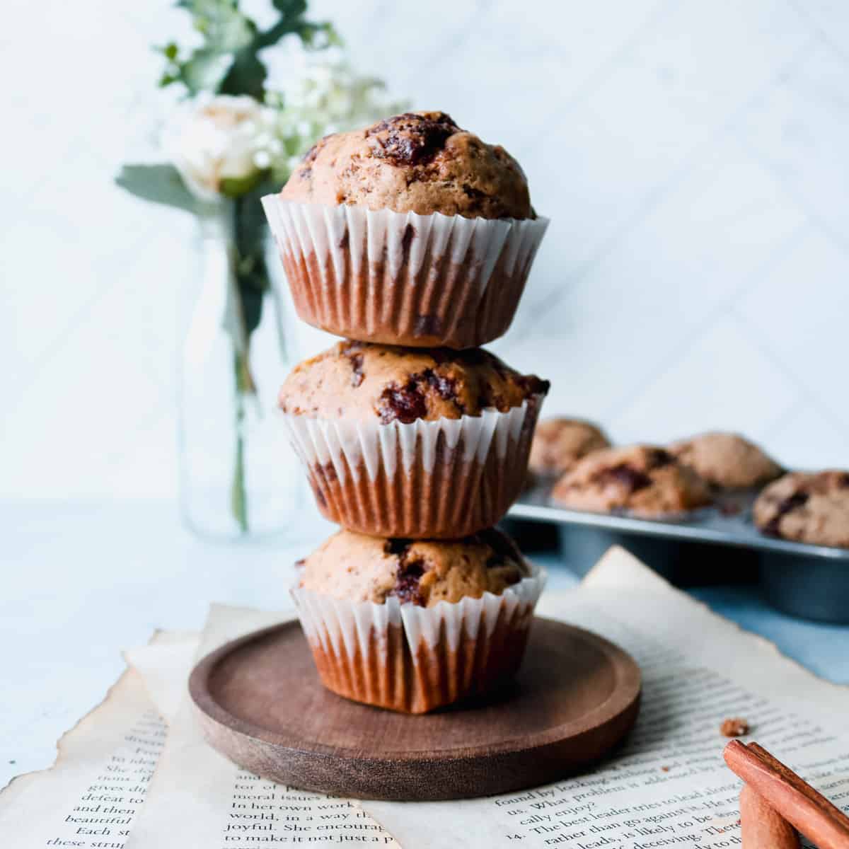 Stack of 3 muffins with more muffins in a tray in the background