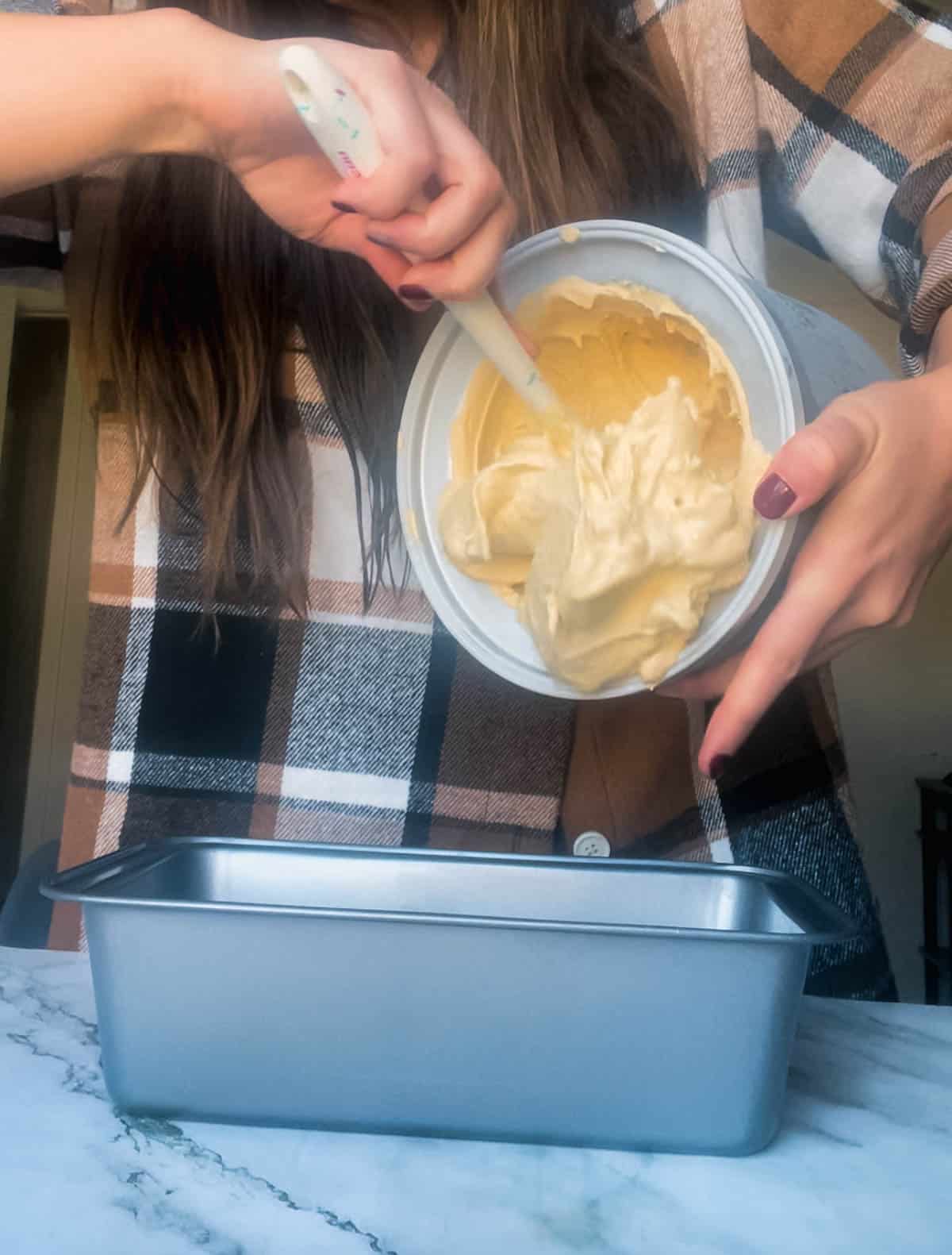 Pouring churned ice cream into container to be frozen.