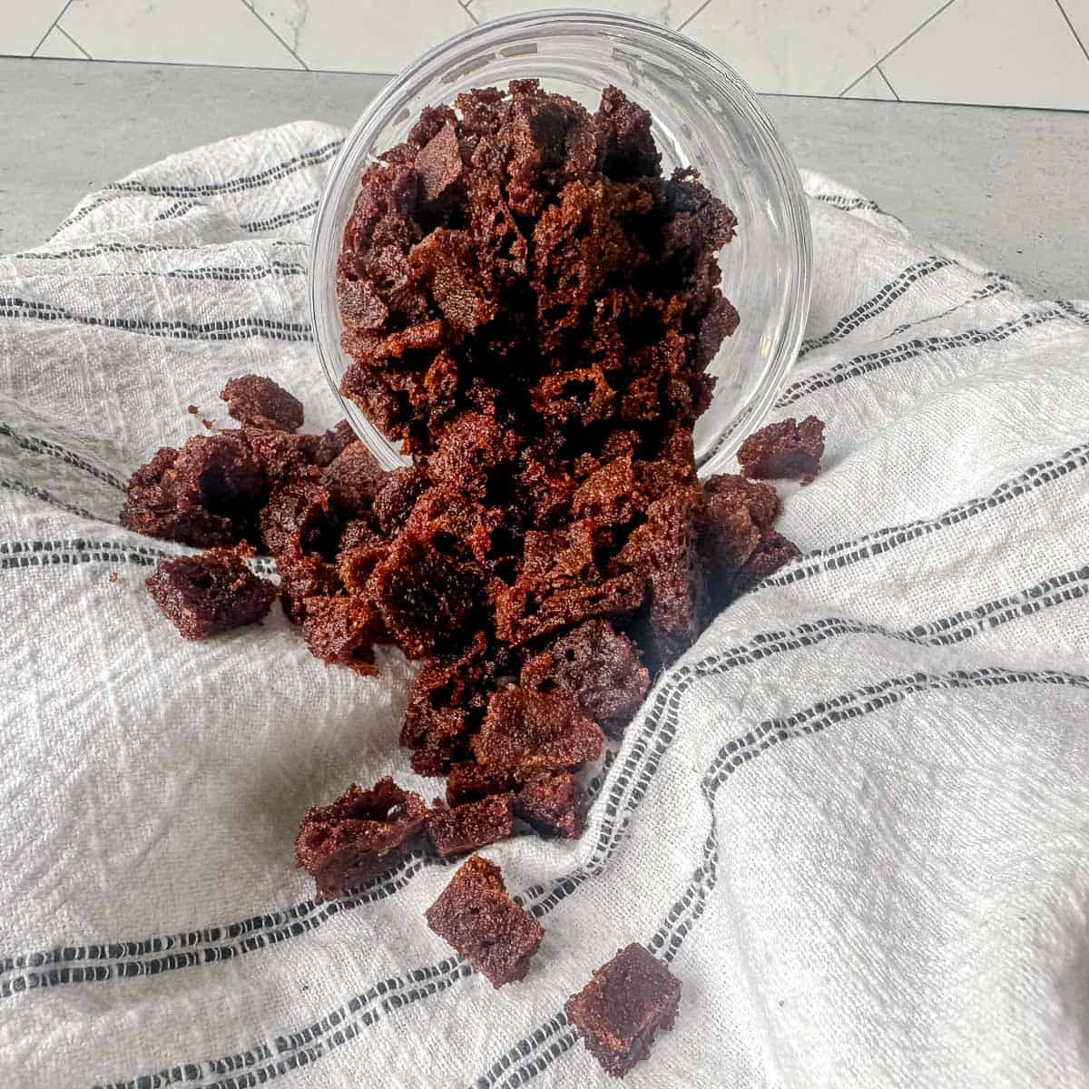 Cinnamon chips spilling out of a jar onto a linen.