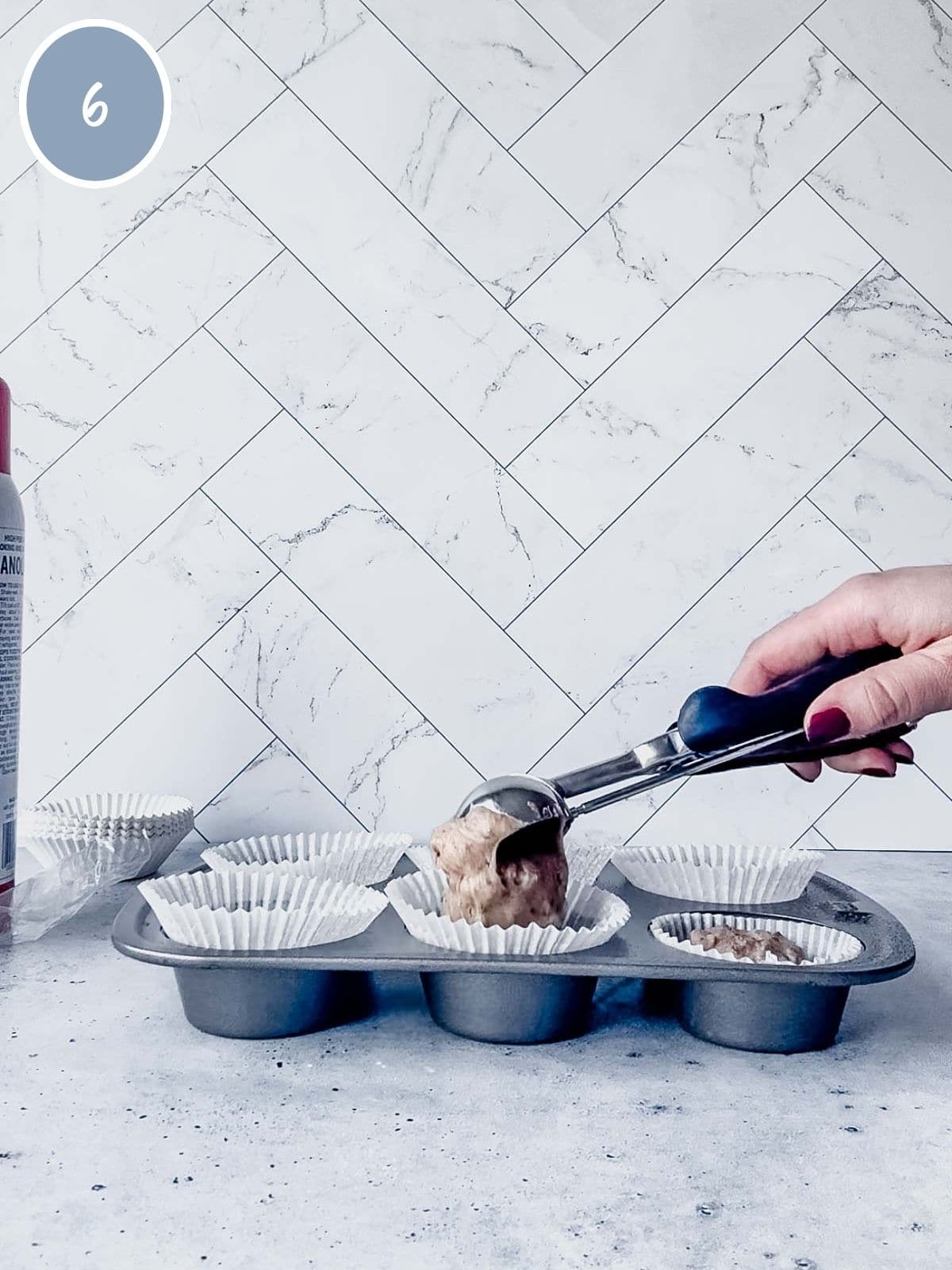 Filling muffin tin with cinnamon chip muffin batter.