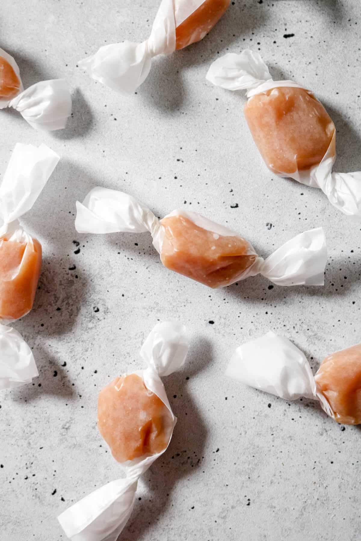 Overhead view of whiskey salted caramels wrapped in wax paper.