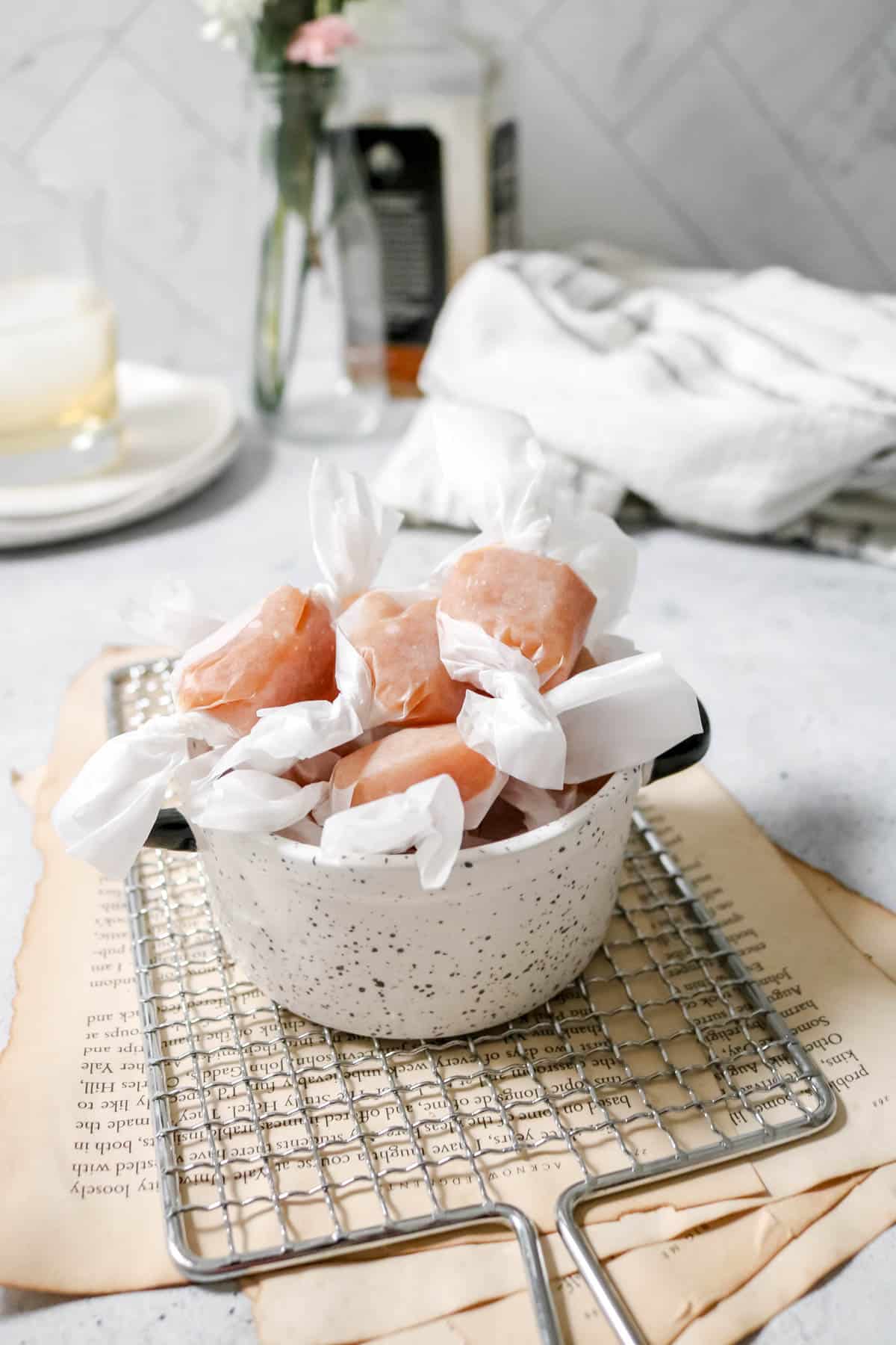 Whiskey salted caramels in a dish and wrapped in wax paper.