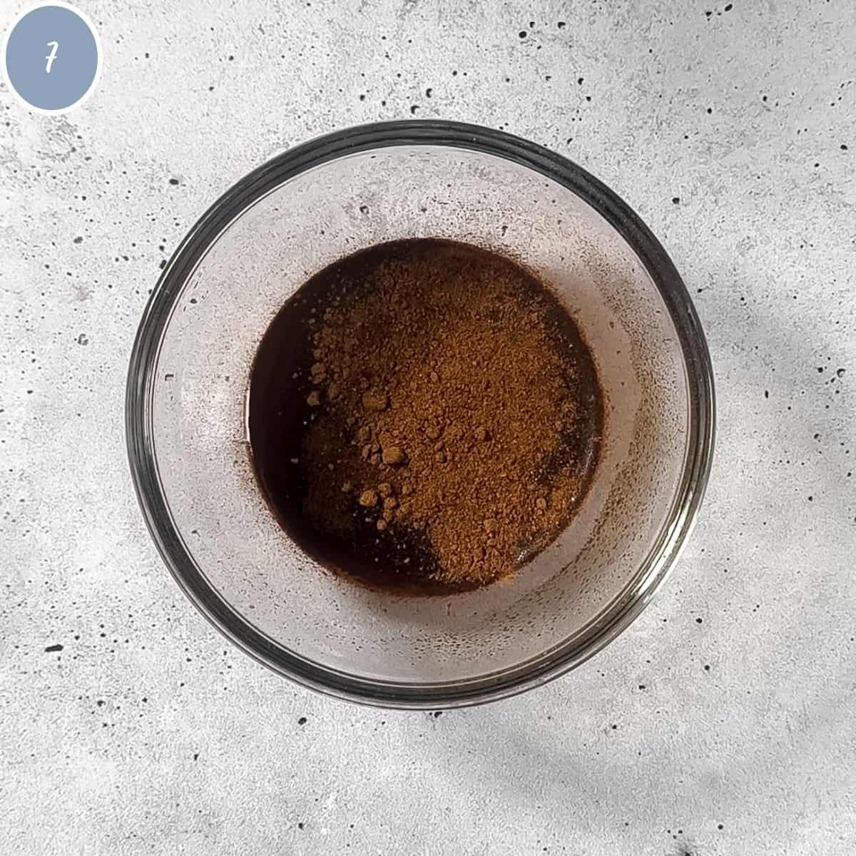 Hot water in a bowl with espresso powder and nutmeg.