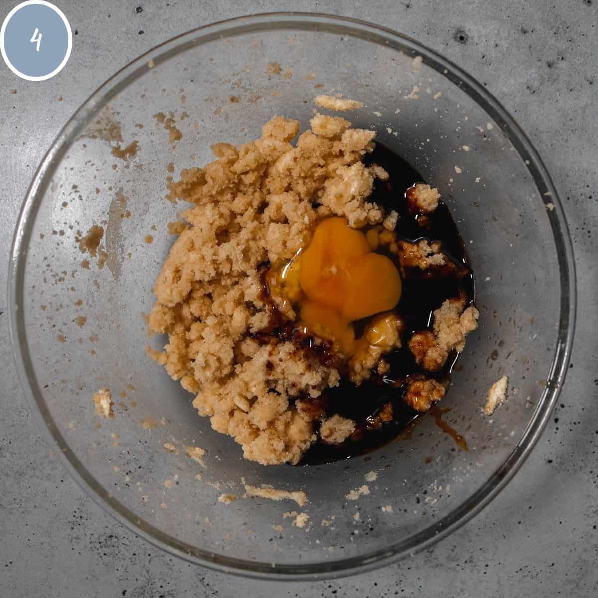 Creamed butter and sugars in a bowl with egg, molasses, maple extract, and vanilla extract.