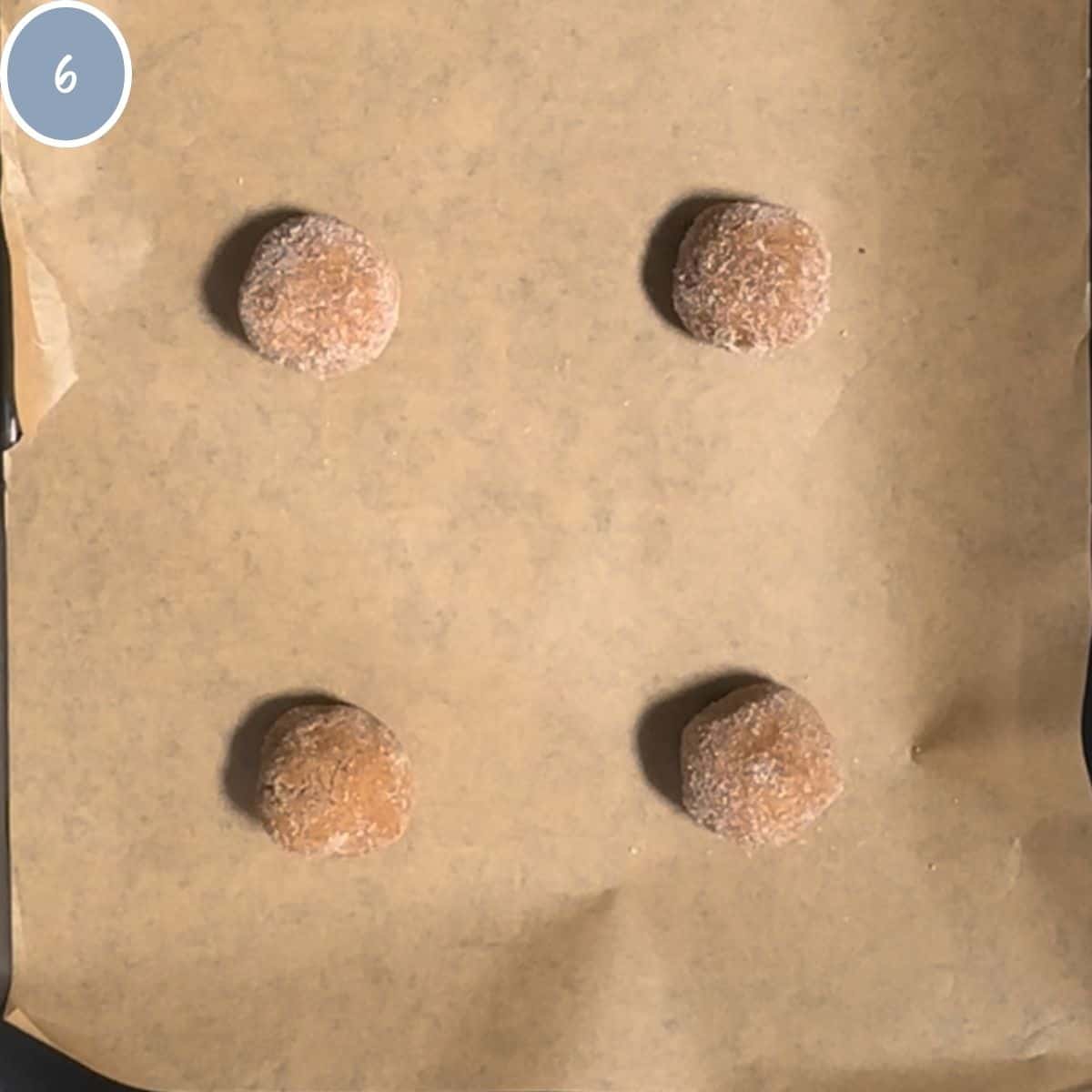 Rolls of cookie dough rolled in sugar and placed on a cookie sheet lined with parchment paper.