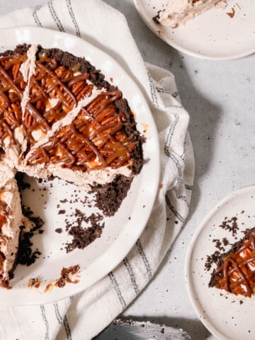 Overhead view of turtle pie with a slice taken out of it and a slice on a plate nearby.