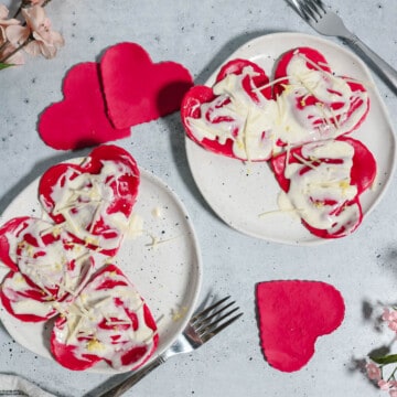 Two plates of beetroot ravioli with lemon ricotta filling and lemon cream sauce.