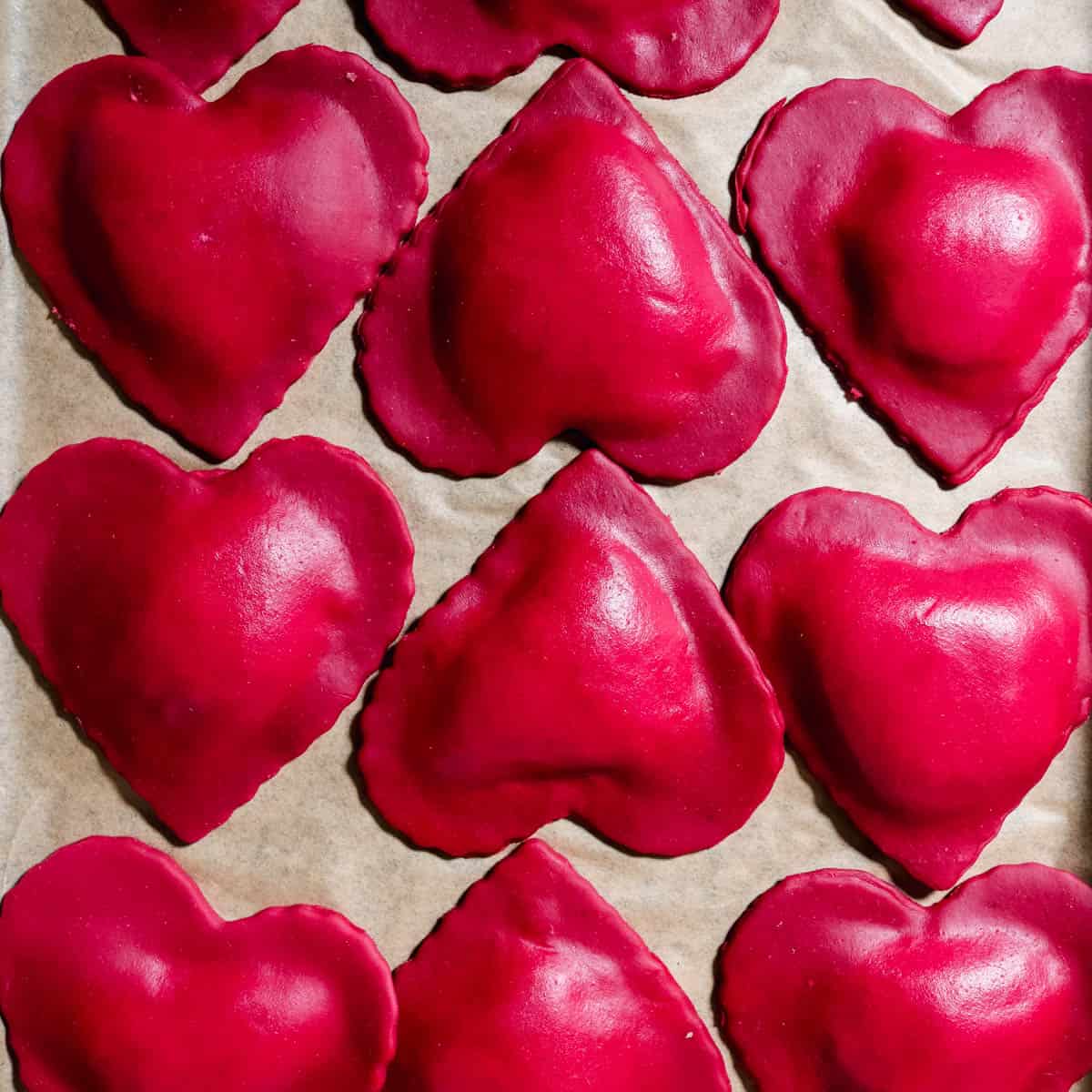 Heart shaped beet ravioli with lemon ricotta filling on a piece of parchments paper.