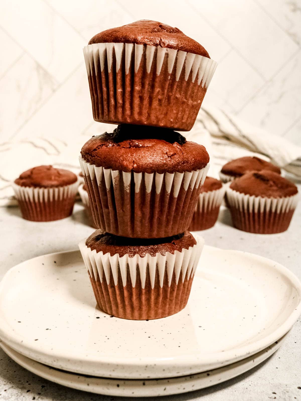 Stack of three sourdough chocolate muffins on a plate.