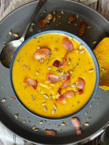 Overhead view of acorn squash soup with bacon, sunflower seeds, parsley on top.