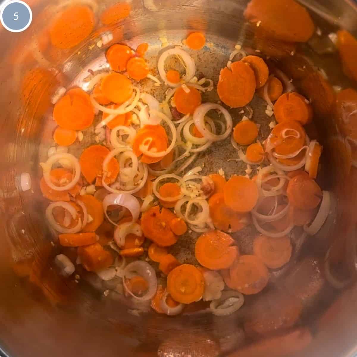 Cooking garlic, shallots, and carrots in a saucepan.