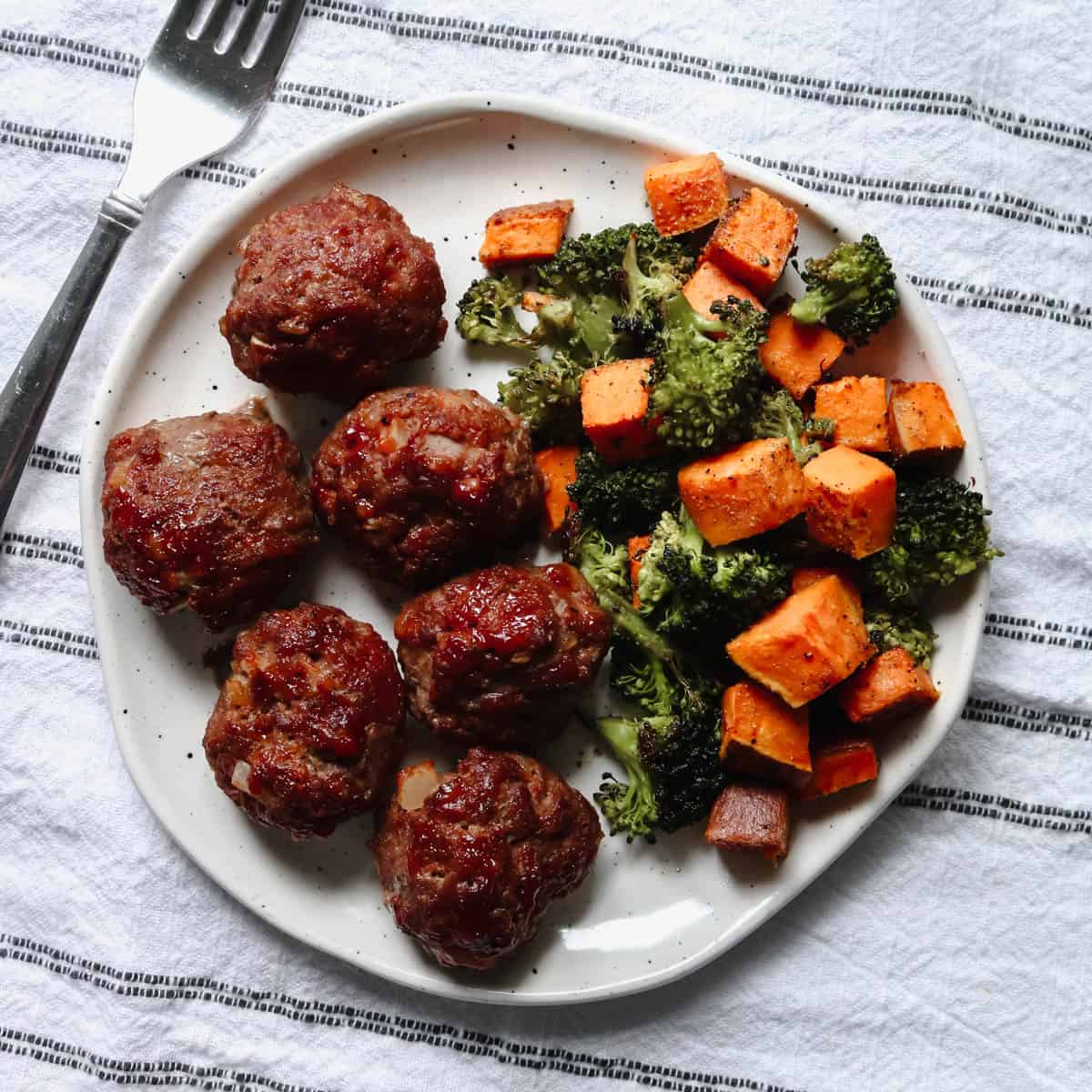 Overhead view of BBQ bison meatballs with sweet potato and broccoli on a plate.