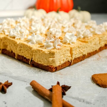 Finished no bake pumpkin cheesecake bars with whipped cream on top.