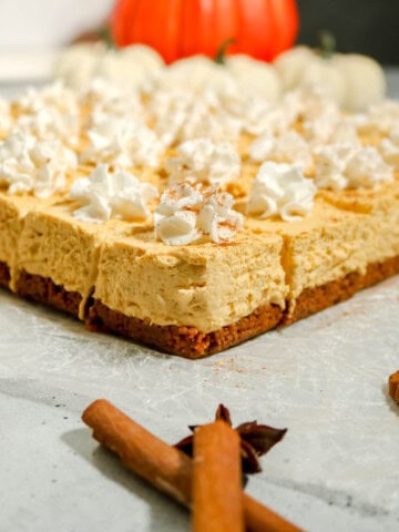 Finished no bake pumpkin cheesecake bars with whipped cream on top.