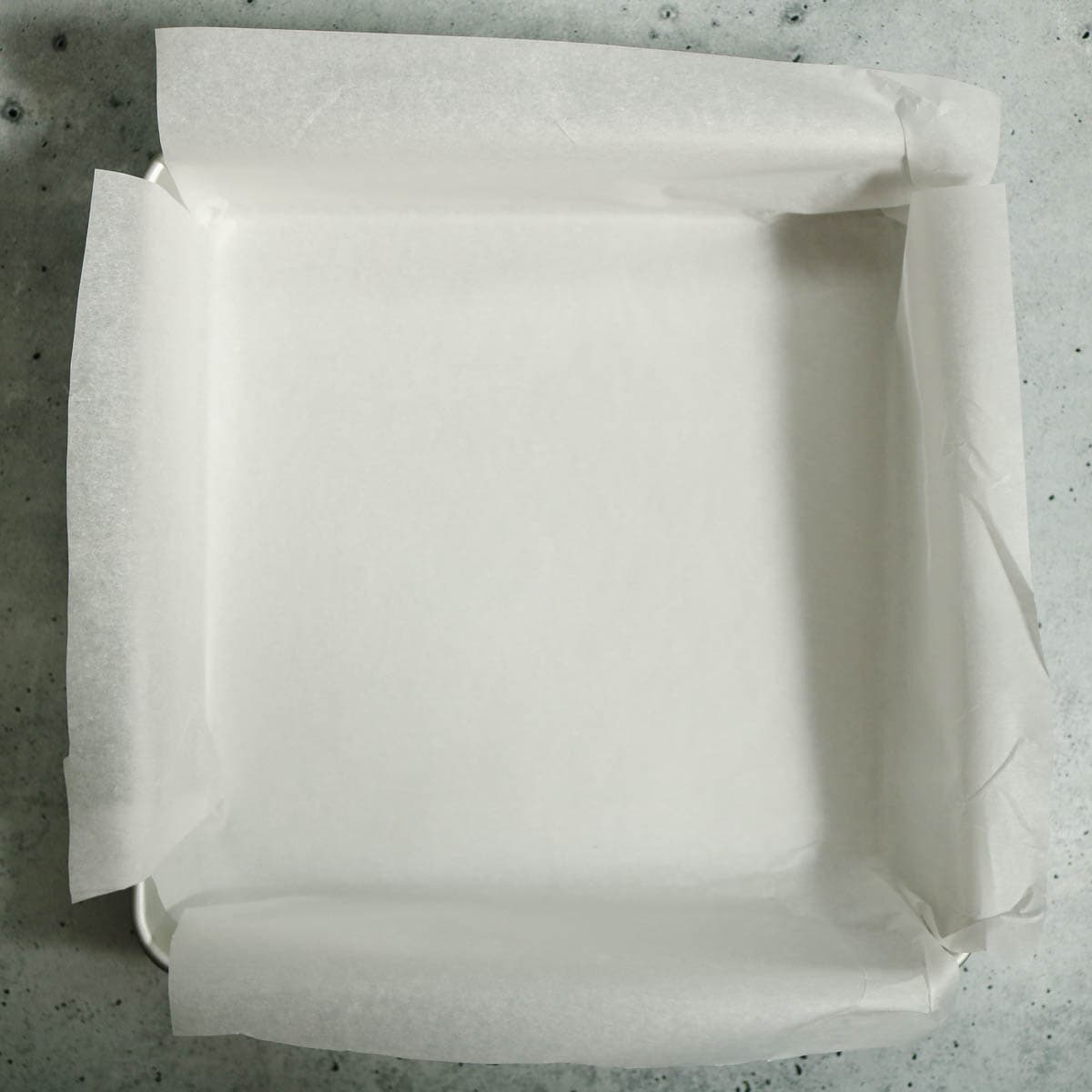 An 8x8 pan lined with parchment paper.