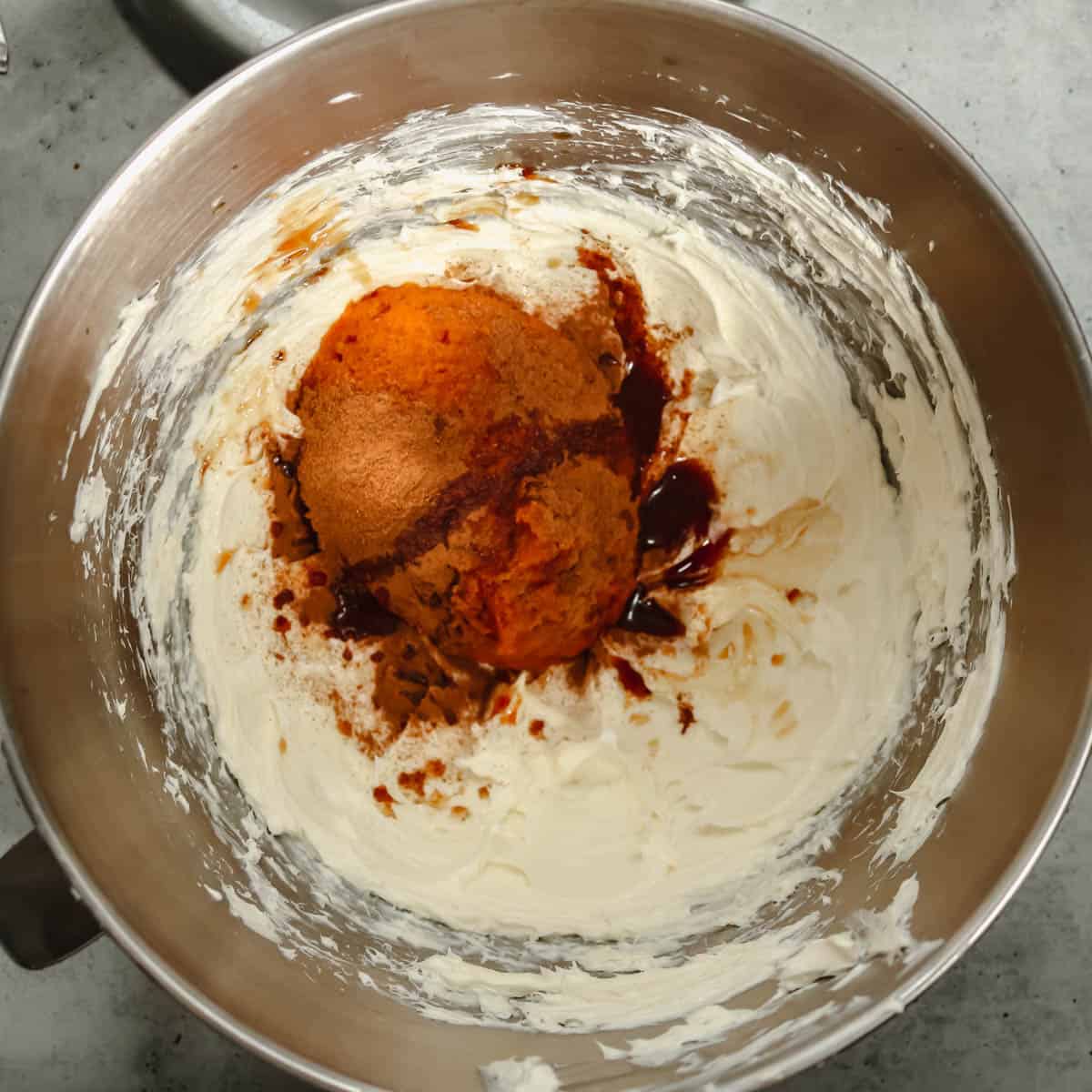 Pumpkin puree, pumpkin spice, and vanilla added to a bowl with cream cheese mixture.