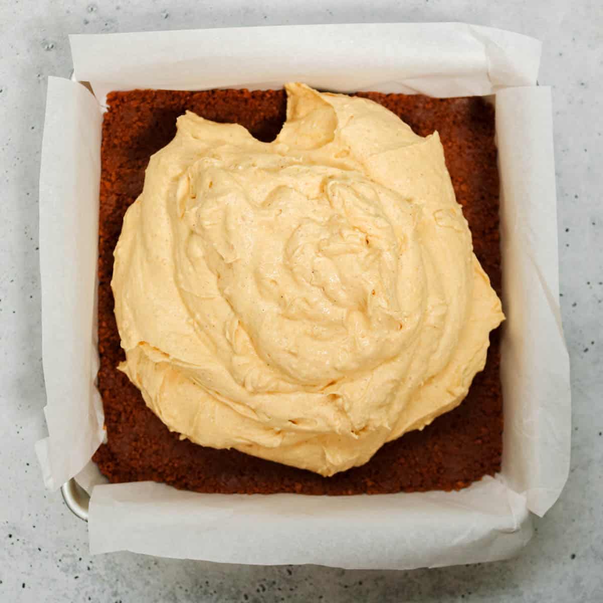 Pumpkin cheesecake on top of Biscoff crust in pan.