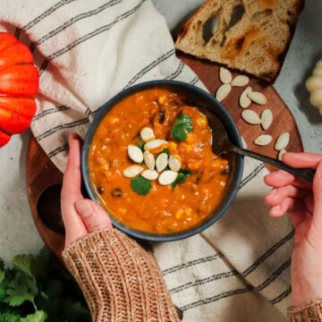 Overhead view of pumpkin chorizo soup with someone taking a spoonful.