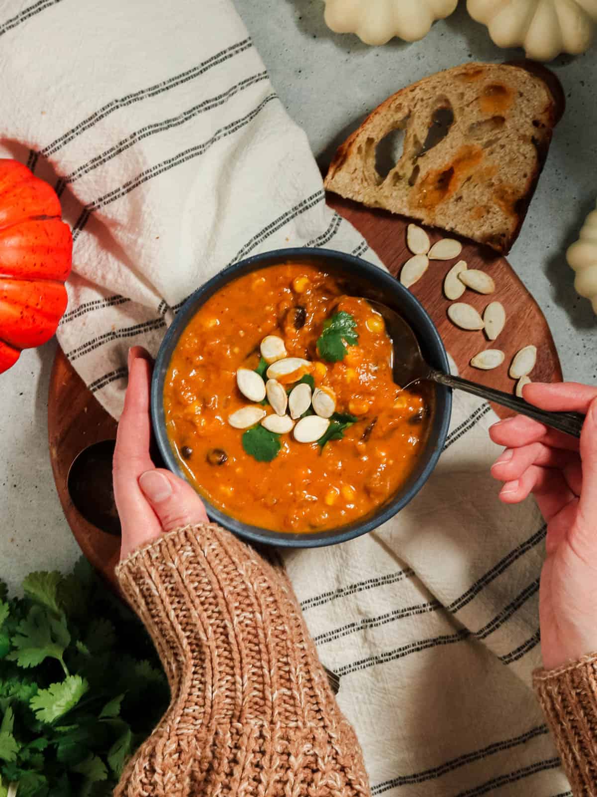 Overhead view of pumpkin chorizo soup with someone taking a spoonful,