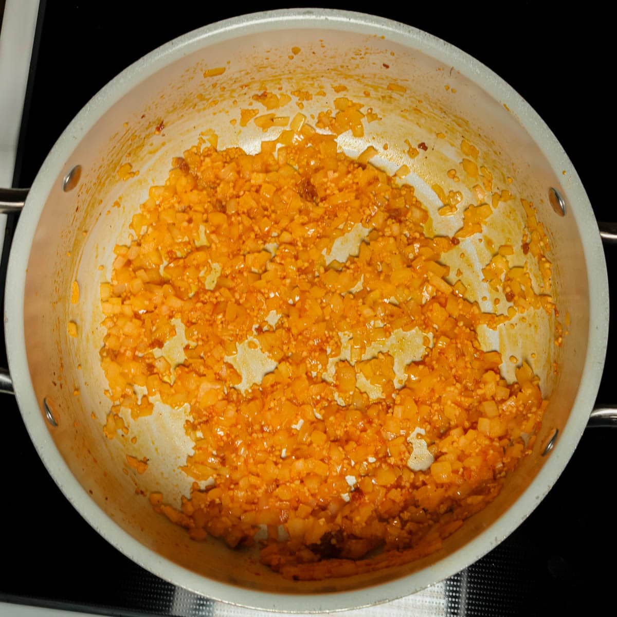 Onion and garlic being cooked in a stock pot.