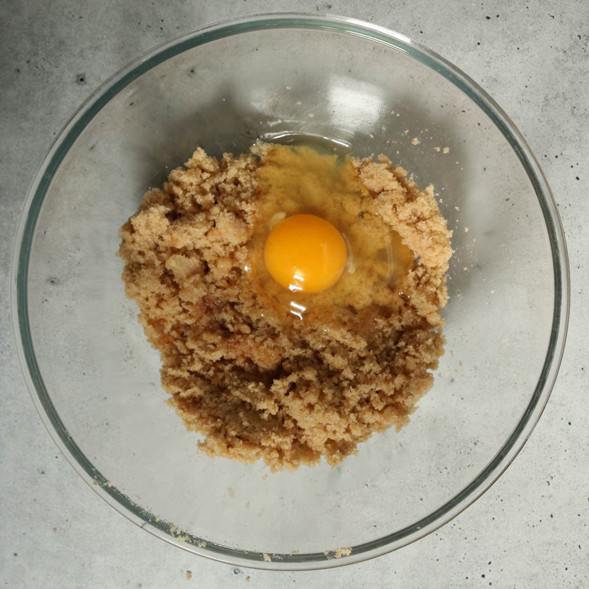 Adding egg and vanilla to a bowl to make cookies.