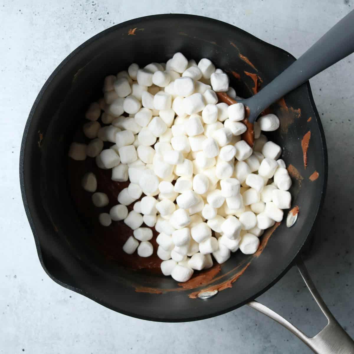 Addition of marshmallows into fudge in a saucepan.