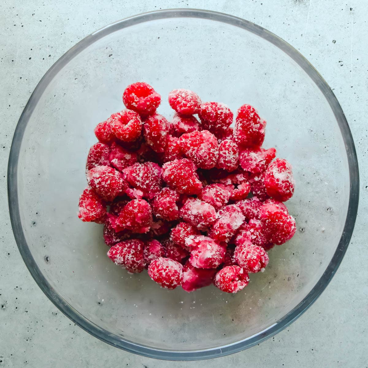 Raspberries tossed in sugar and cornstarch in a bowl.