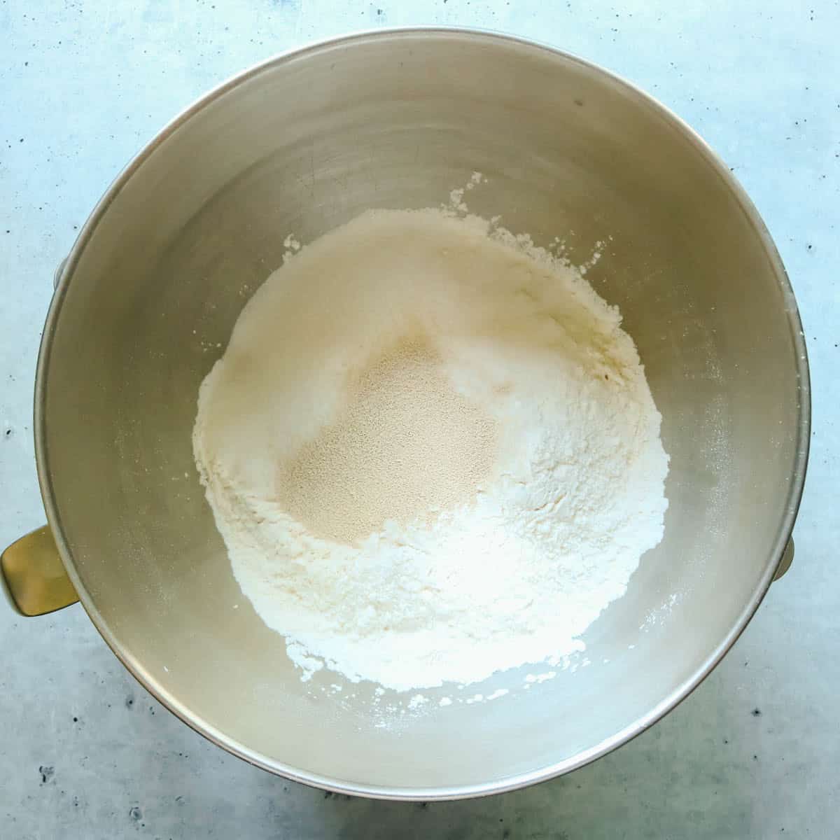 Flour, sugar, yeast and salt added to a mixing bowl.